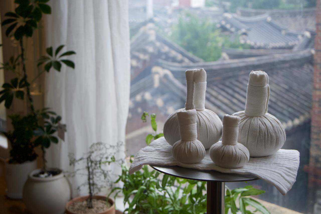 Herbal compresses with a hanok backdrop