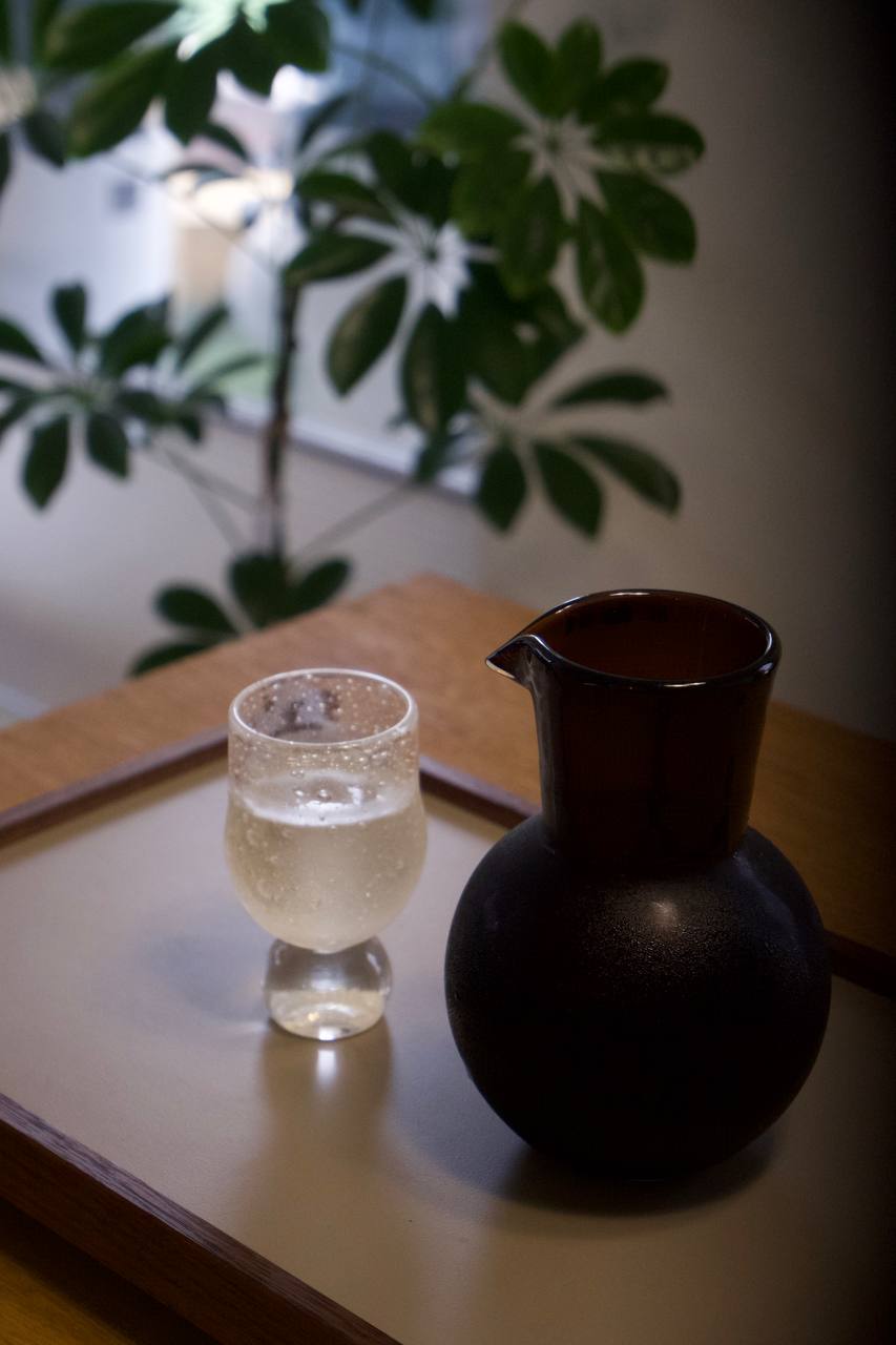 A glass and carafe on a wooden tray